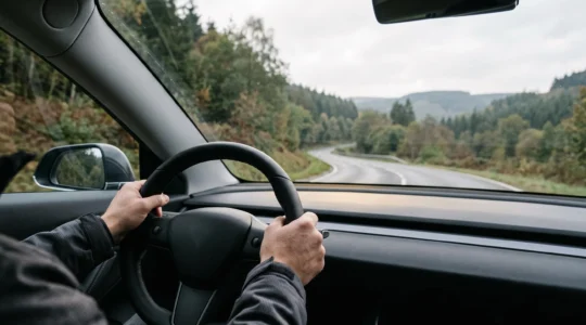 Conducteur passionné au volant d'une voiture électrique sur une route sinueuse des Ardennes belges, incarnant la nouvelle émotion de conduite