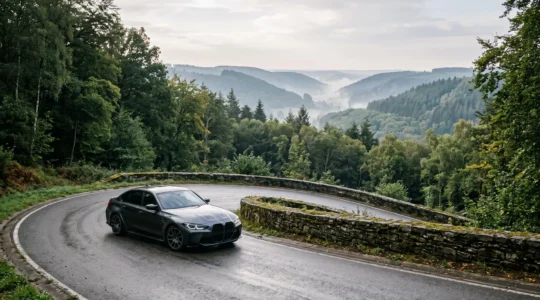 Voiture de sport engagée avec fluidité dans un virage encaisse d'une route forestiere ardennaise au petit matin